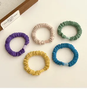 Détail de cinq chouchous en velours plissés avec boucles mates de couleurs assorties