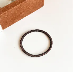 Détail d'un élastique à cheveux bronze sans couture avec texture en spirale