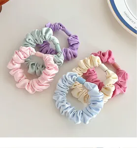 Set of six pastel scrunchies with square buckle details on a decorative plate