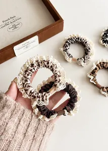 Close-up of leopard print hair scrunchies with white lace edges and high elastic bands