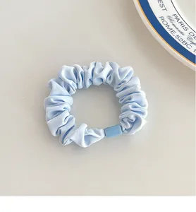 Detailed close-up of light blue fabric scrunchie with matching plastic connector