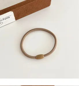 Macro-opname van dik koffiebruin haarelastiekje met een cilindrische harsconnector
