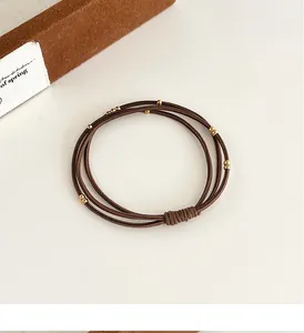 Vue détaillée des élastiques à cheveux marron triple épaisseur avec perles dorées