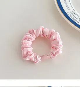 Detailed view of pink fabric scrunchie with matte square bead on neutral surface