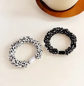Dettaglio di elastici scrunchie in raso a pois bianchi e neri su un vassoio decorativo