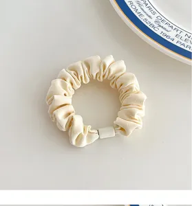 Detailed texture of cream pleated fabric hair scrunchie with elegant resin block