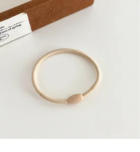 Detailopname van de elastische haarelastiek met matte harskraal in melkkoffiekleur