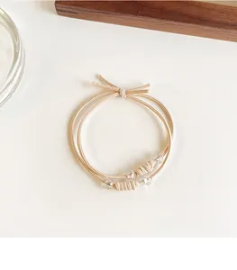 Detail van beige elastische gevlochten haarelastiekjes met kristallen kralen en knopen