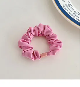 Close-up of a pink fabric scrunchie with textured ribs and a matching plastic buckle