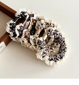 Set of 5 leopard print scrunchies with white lace trim and rectangular accents