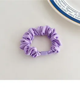Detailed close-up of a purple pleated scrunchie with matte texture and buckle detail