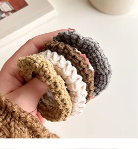 Détail de chouchous en tricot velours élastique aux tons terreux tenus à la main