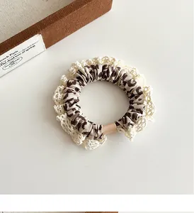 Close-up of leopard print scrunchie with delicate white lace trim on white background