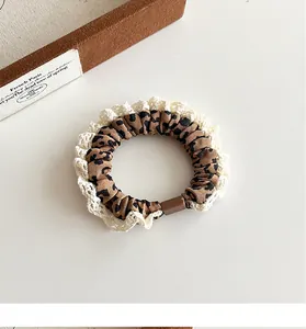 Close-up of leopard print hair scrunchie with delicate lace trim and brown buckle