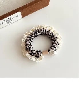Detailed macro of leopard print scrunchie featuring elegant off-white lace edges