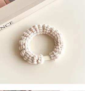 Gros plan d'un chouchou en chenille beige avec texture velours et boucle en plastique