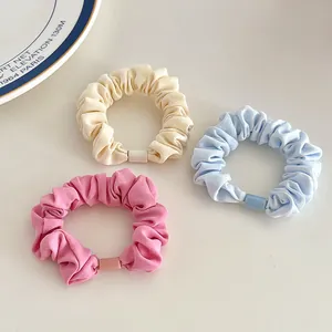 Three-piece set of pastel elastic hair scrunchies in cream, blue, and pink fabric