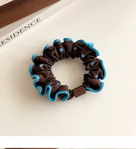 Detalle de coletero marrón con lunares con bordes azules rizados y hebilla de plástico