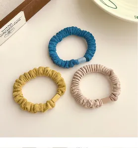 Lot de trois chouchous en velours bleu, jaune et beige avec boucles en plastique