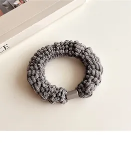 Vue détaillée de la texture du chouchou en velours tricoté gris foncé avec boucle en résine
