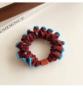 Detalle de coletero burdeos con lunares, bordes de encaje azul y adorno rojo