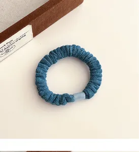 Détail d'un chouchou en velours bleu avec texture plissée et boucle mate résistante