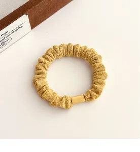 Détail d'un chouchou en velours jaune moutarde avec texture de tissu et boucle décorative