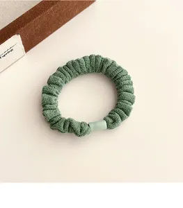 Détail d'un chouchou en velours vert foncé avec texture côtelée et fermoir vert