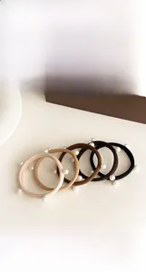 Dettaglio di quattro elastici per capelli con perle in colori neutri su base in legno