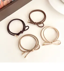 Close-up of four elastic bow hair ties in earth tones with elegant gold metal tips