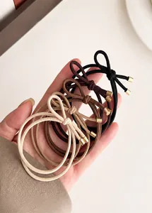 Detail of 4-piece bow hair tie set featuring multi-strand elastic cords and gold metal ends