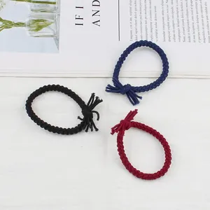 Three braided hair ties in black, navy, and wine red with tassel knots on a white surface