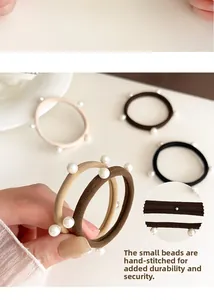 Dettaglio di perline applicate a mano su elastici per capelli con fissaggio resistente