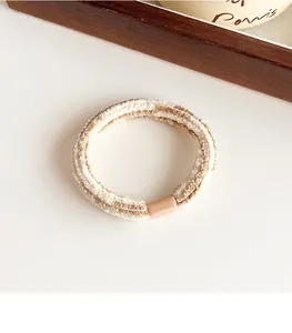 Nahaufnahme gestreiftes Plüsch Haargummi in Beige und Khaki mit mattem rosa Verschluss