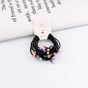 Detail of black elastic hair bands with matte colorful beads on white card packaging