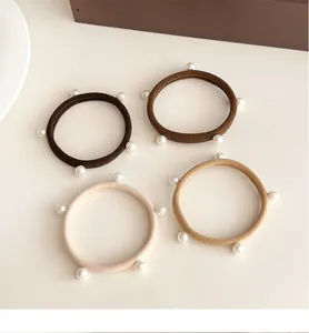 Dettaglio di quattro elastici per capelli color terra con eleganti perle bianche