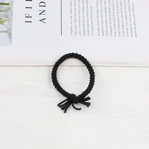 Detail of hand-woven black twisted braided hair tie with a decorative tassel knot