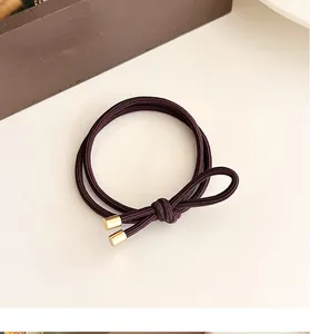 Detail of high-elasticity double-strand hair tie with gold metal fixings and bow knot