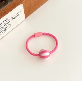 Detalle de goma de pelo rosa con cuenta a rayas y caja de joyería decorativa