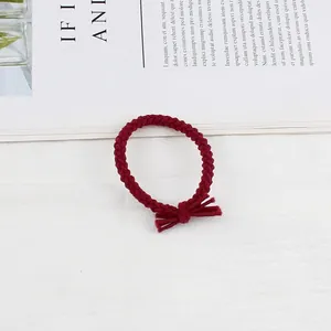 Detail of burgundy braided elastic hair tie with a minimalist knot on a white surface
