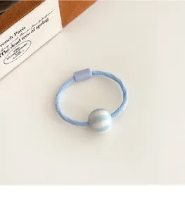 Detalle de goma de pelo azul claro con cuenta a rayas y cierre rectangular sólido