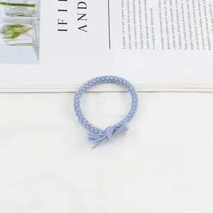 Detailed view of light blue braided hair tie with elegant decorative bow knot texture