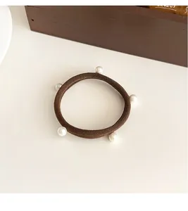 Primo piano di un elastico per capelli marrone caffè con cinque perle bianche