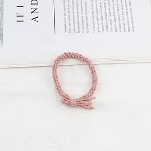 Pink braided hair tie with a small bow knot detail on a white textured background