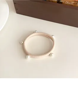 Dettaglio di elastico per capelli color caffellatte con cinque perle bianche lucide