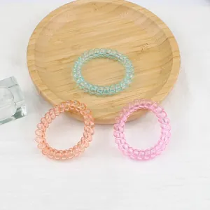 Élastiques à cheveux spirales bleu, orange et violet sur un plateau en bois