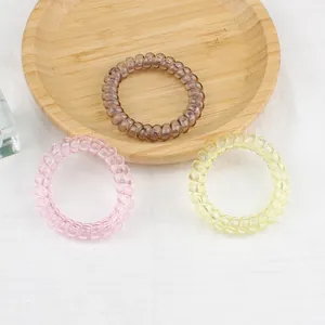 Élastiques à cheveux spirale rose, marron et jaune sur un plateau en bois