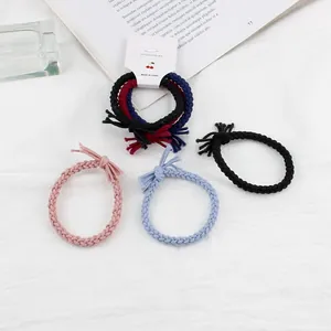 Set of 3 braided thick twist hair ties with tassels on a white textured background