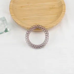 Dettaglio di un elastico per capelli a spirale trasparente su un vassoio di legno