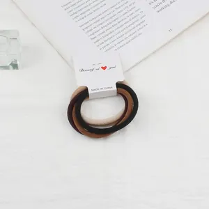 Close-up of elastic hair ties in brown and beige colors with a branded paper card